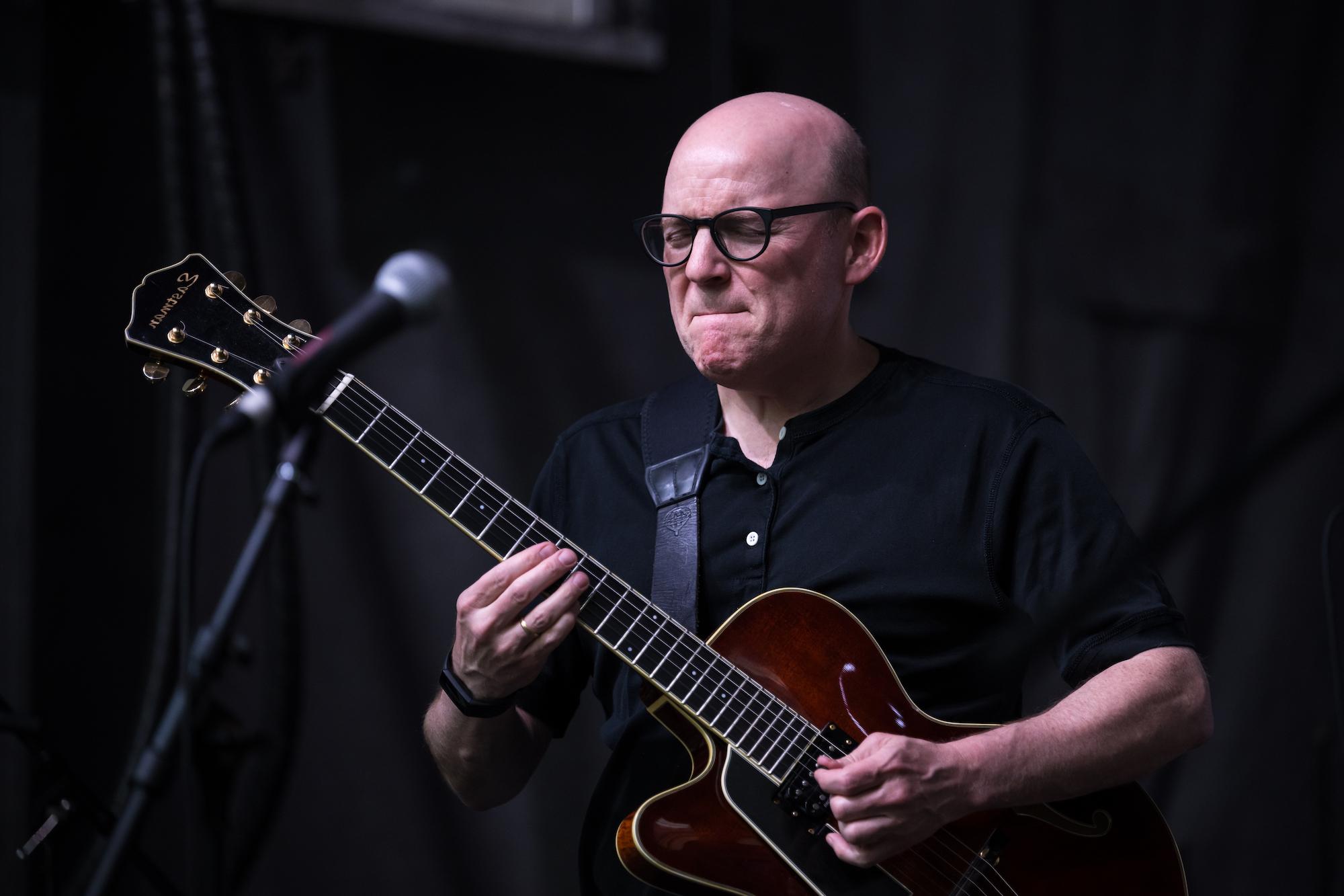 Man in glasses playing jazz guitar