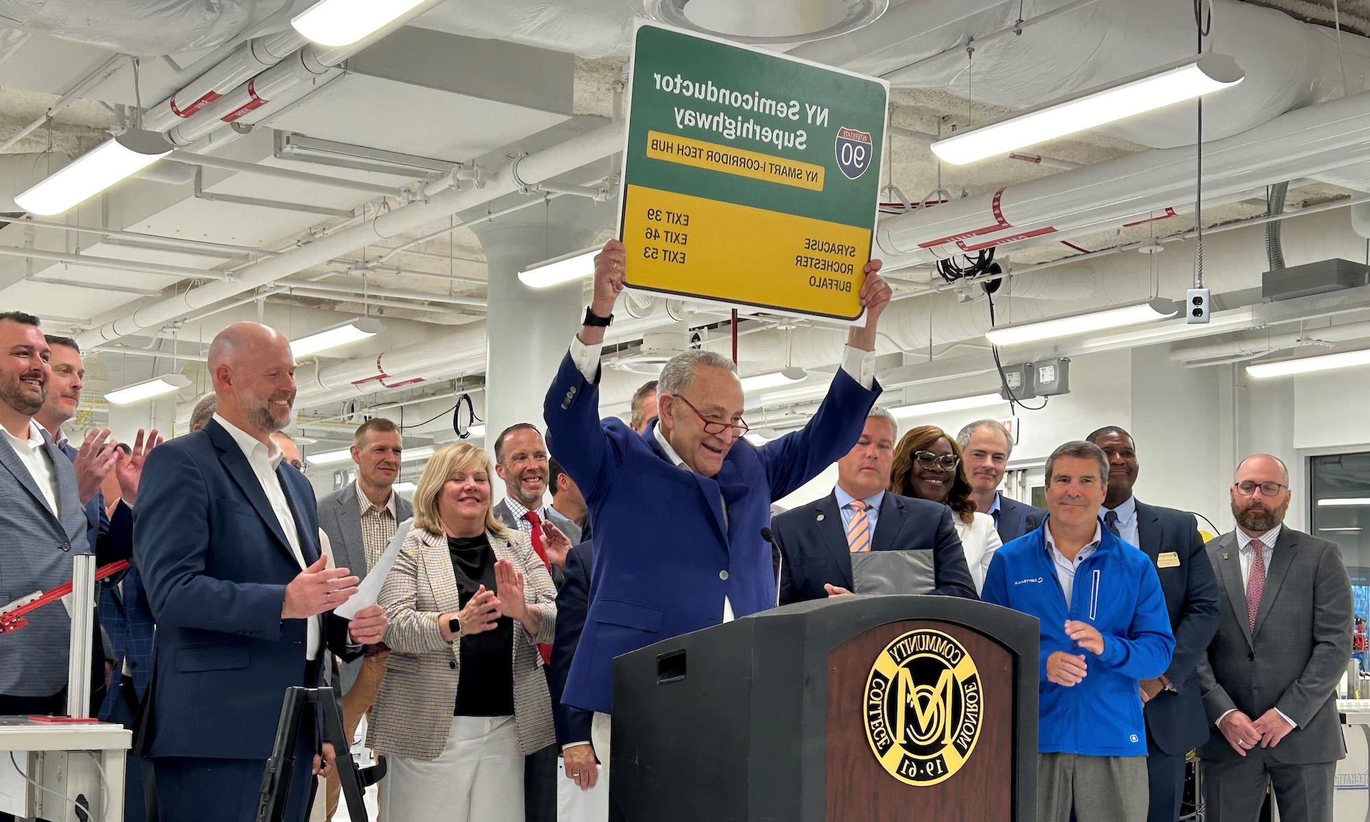 Senator Schumer, in front of other leaders, holds sign that says Route 90, "NY Semiconductor Superhighway."